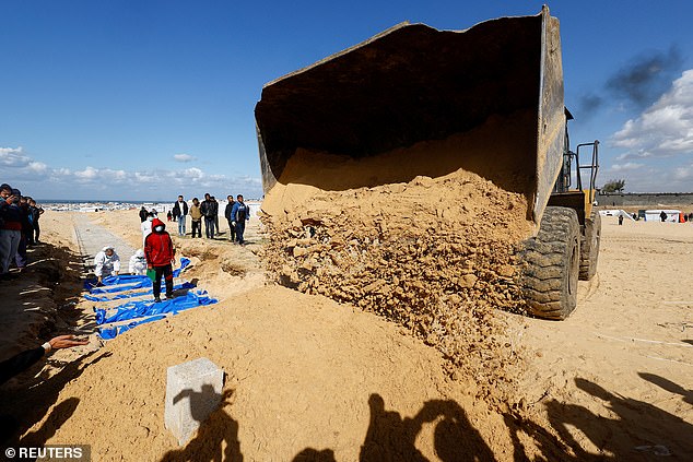 People bury Palestinians, including those killed in Israeli attacks and fire, after their bodies were released by Israel, amid the ongoing conflict between Israel and the Palestinian Islamist group Hamas, at a mass grave in Rafah