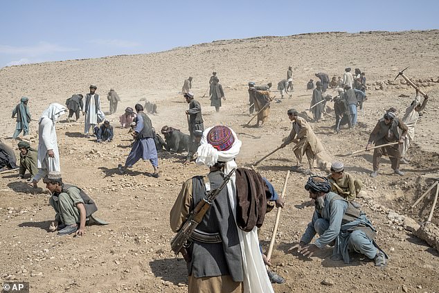 A Taliban fighter watches over workers building a road in a remote area of ​​Afghanistan