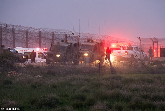 Israeli soldiers walk alongside military vehicles and ambulances as the conflict continues between Israel and the Palestinian Islamist group Hamas, near the fence on Israel's border with Gaza, Israel January 22