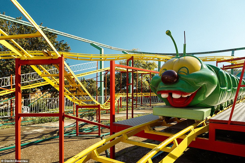 This smiley roller coaster is one of the attractions photographed by Dimitri Bourriau during his visit to the abandoned Lucky Star Park in Larnaca, Cyprus.  Supposedly it once received thrills and excitement from children riding in the carriages, but now stands motionless