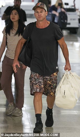 The 45-year-old football legend was spotted making his way through the arrivals hall looking relaxed in a black T-shirt, printed shorts and a matching baseball cap.