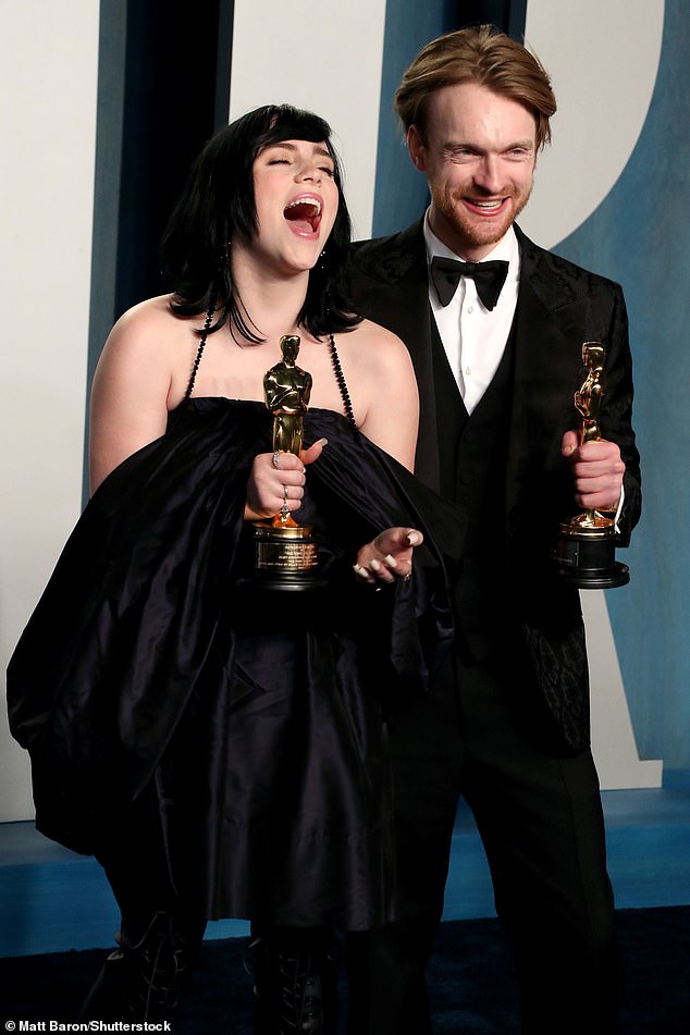 Radiant: Billie wore a black satin mini dress for the bash, which was a far cry from the huge ruffled dress she took to the red carpet in at the start of the ceremony (pictured with her brother Finneas)