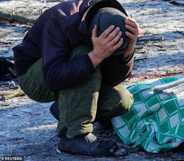 A man was seen mourning the death of his wife, who was covered with a green and white cloth