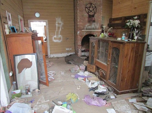 An image from the property ad shows a graffiti-painted penis and a homophobic slur under a pentagram decorated with feathers in the living room (pictured)