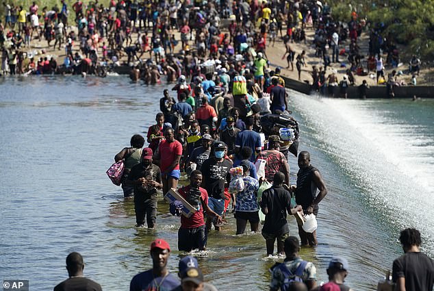 Pictured: Haitian migrants use a dam to cross the border into the United States in 2021