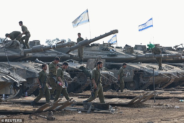 Israeli soldiers walk next to tanks near the Israel-Gaza border, in southern Israel (January 1, 2024)