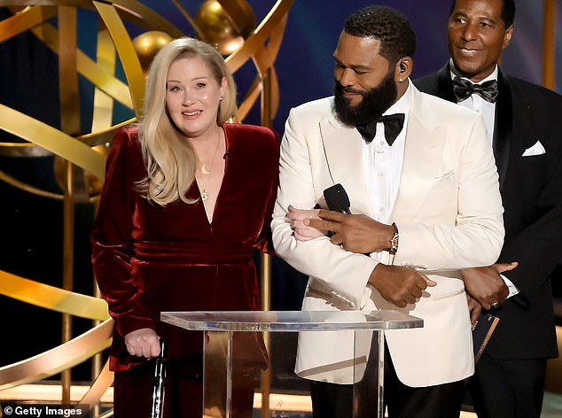 The 52-year-old Dead To Me star brought the crowd to their feet as she walked on stage in a stunning red velvet dress;  seen with host Anthony Anderson