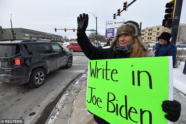 Melissa Hinebauch of Concord waves at cars as she promotes the write-in campaign to put President Joe Biden's name on the New Hampshire Democratic Party primary ballot