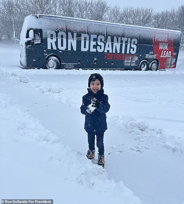 A bundled up Mason DeSantis, five, shows off a snowball he made in Iowa while knocking on the door with his mother