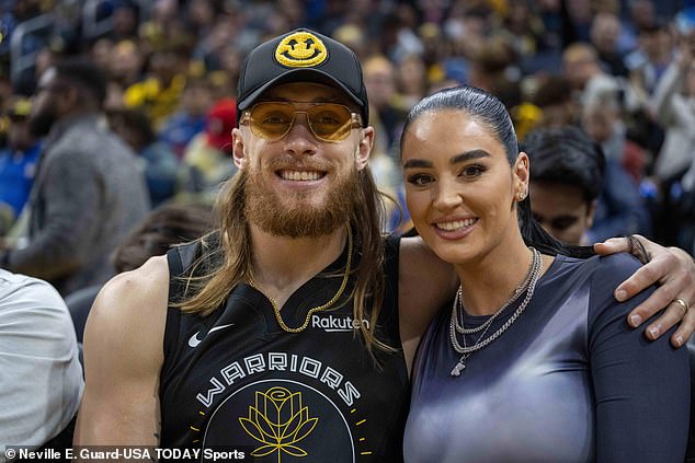 The loved-up couple poses for a photo while standing courtside during the game at Chase Center