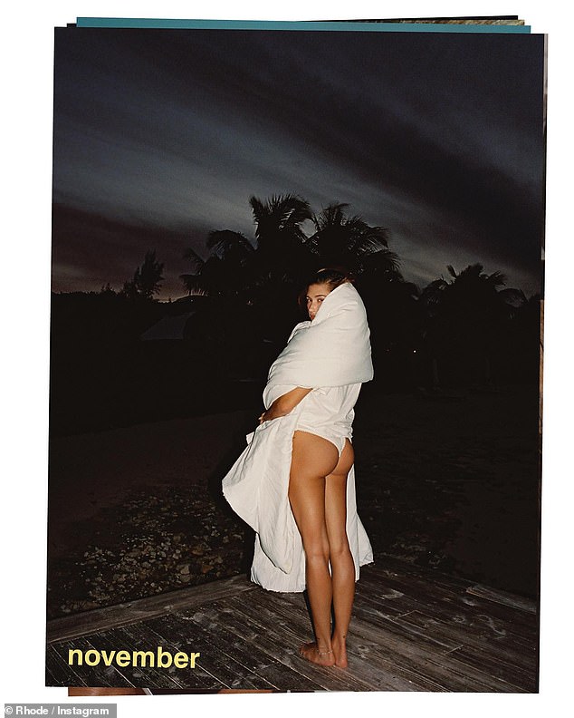 Hailey Bieber showed off her perky derriere in a white thong as she wore a blanket around her shoulders.  The model and businesswoman, 27, showed off her backside in the cheeky snap as she posed for her Rhode 2024 calendar