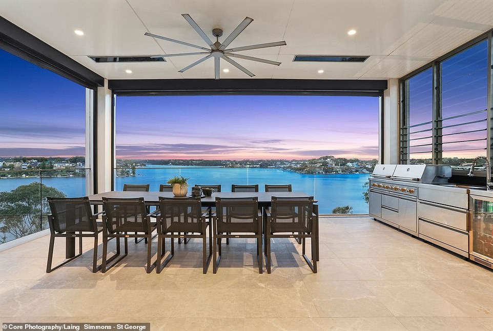 The living room opens onto a covered terrace with an outdoor kitchen and spectacular views over the river