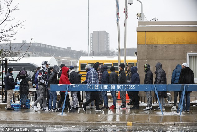 A group of migrants receive food outside the migrant landing zone during a winter storm on January 12, 2024 in Chicago, Illinois