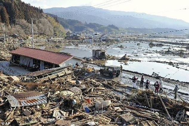 Rescue workers stand near completely destroyed houses at a port in Rikuzentakada in Iwate Prefecture, northern Japan, in 2011
