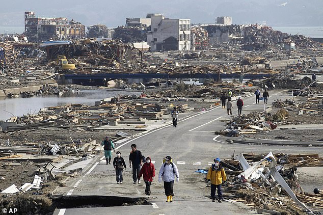People walk along a road among the rubble of destroyed buildings in Minamisanriku city, Miyagi Prefecture, northern Japan, in 2011
