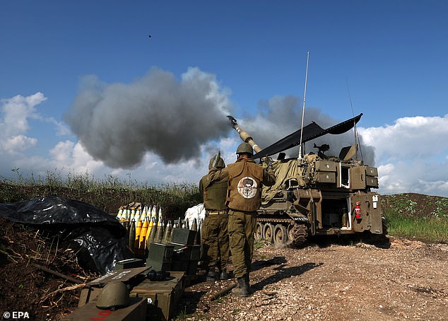 An Israeli artillery fires on a target in Lebanon from a secret location on the Lebanon-Israel border.  The soldier on the right has a jacket with a graffiti of a target with Hezbollah leader Hassan Nasrallah