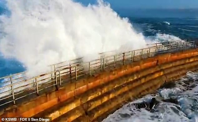 A seawall is seen being shelled in La Jolla, one of several coastal communities under high surf warnings as the unusual weather continues