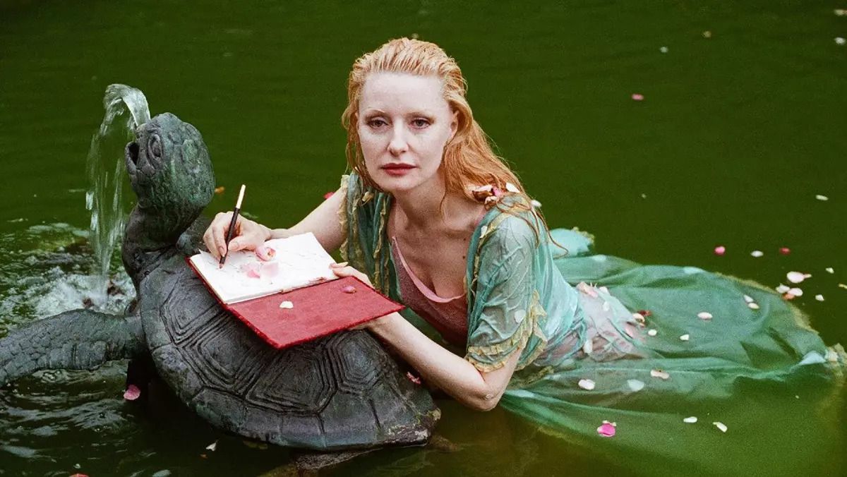 Photo Shere Hite lies in a pool of water and writes in a red diary on top of a stone turtle fountain in the documentary 'The Disappearance of Shere Hite'.