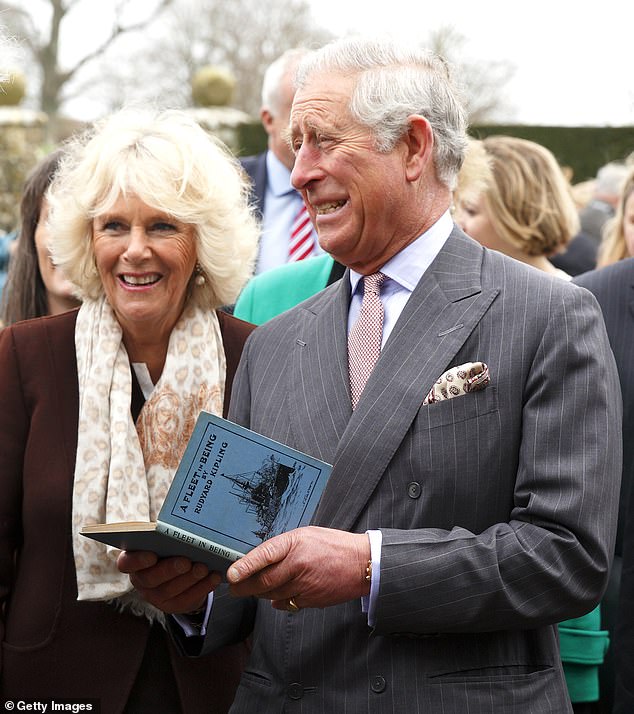 King Charles and Camilla look at a copy of Rudyard Kipling's 'A Fleet in Being' during a visit to Burwash in East Sussex in 2014