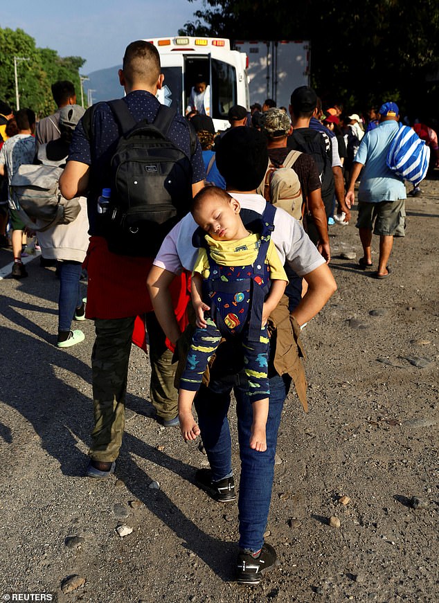 Migrants walk along a road on Friday in Huixtla, a city in the southern Mexican state of Chiapas.  The group is part of the first caravan that will form in 2024 and they hope to reach Mexico's northern border area with the United States