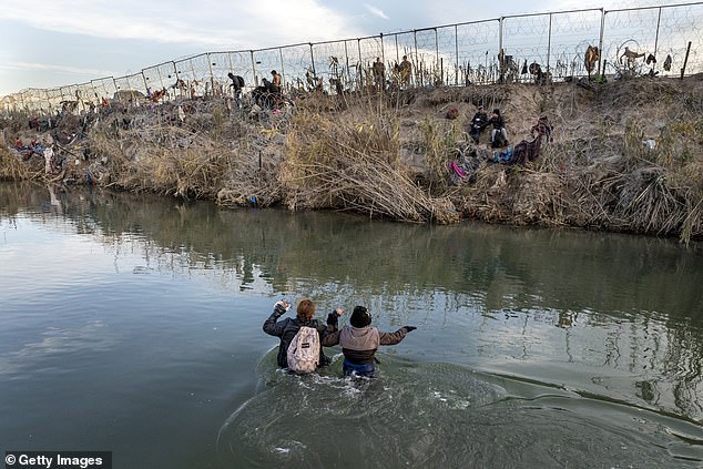 Migrants walk across a shallow part of the Rio Grande as they try to reach the border with the United States