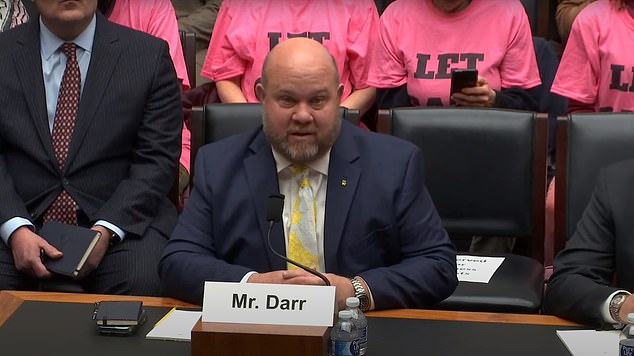 The group of female protesters strangely sat behind the witnesses to appear on the livestream of the hearing