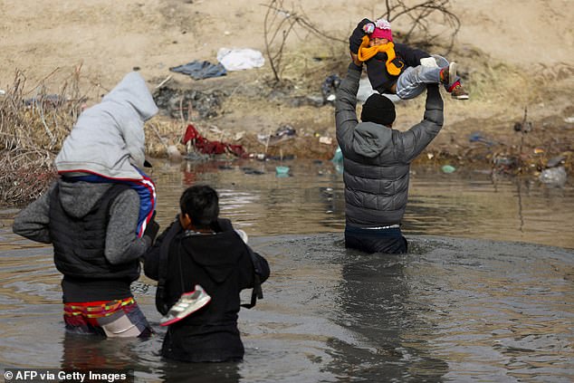 Migrants crossing the Rio Grande River illegally into the US are keeping children above the water