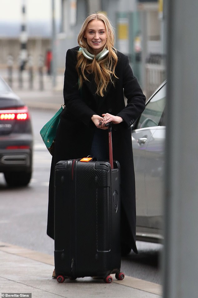 Sophie Turner looked in good spirits during an outing at Heathrow Airport, where she was spotted wearing a gold band on her engagement finger