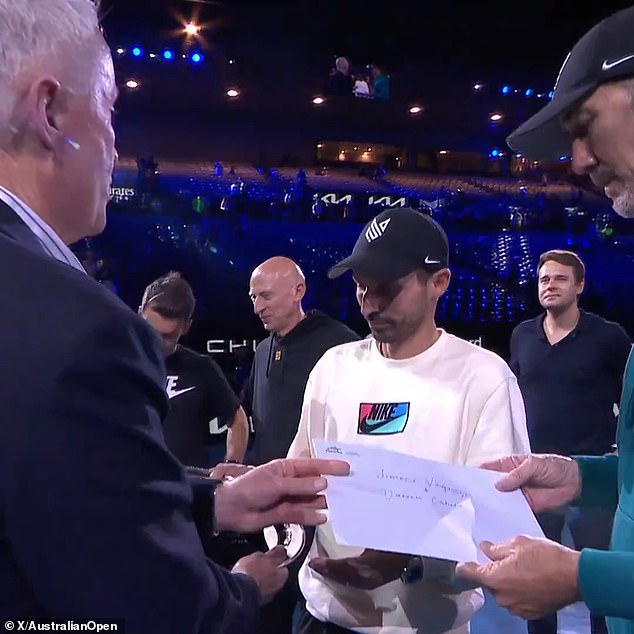 Craig Tiley (left) presented Jannik Sinner's coaches Simone Vagnozzi (centre, in white) and Darren Cahill (right) with an envelope with their names after the Italian's victory