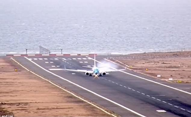 The plane hovers above the runway before abruptly hitting the ground, creating a cloud of smoke on impact, before coming to a stop.