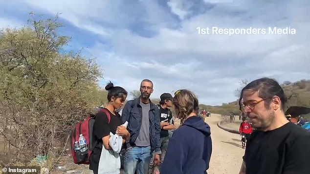 The migrant man (second from left) said to the reporter: 'You're going to know who I am'