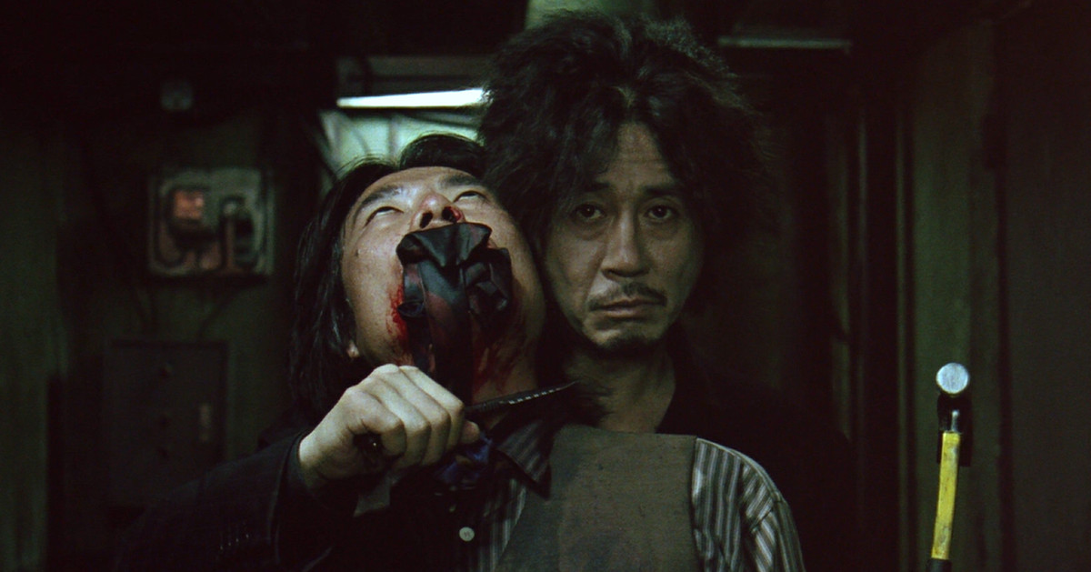 Choi Min-sik as Dae-su Oh who holds a gagged man hostage with a knife and hammer in Oldboy.