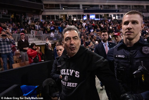 A protester is escorted by police during the campaign event of Republican presidential candidate, former President Donald Trump, at the SNHU Arena Manchester