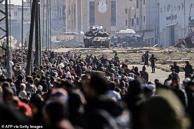 An Israeli tank and other military vehicles guard a position as Palestinians flee Khan Yunis in the southern Gaza Strip on January 26, 2024