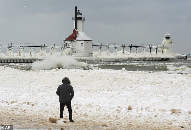 Snow and ice cover Michigan's St. Joseph Lighthouses as waves crash along the Lake Michigan ice shelf formed along Tiscornia Beach