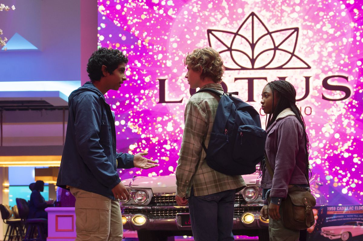 Grover talks to Percy and Annabeth as they stand in front of the glitzy entrance to the Lotus Hotel and Casino