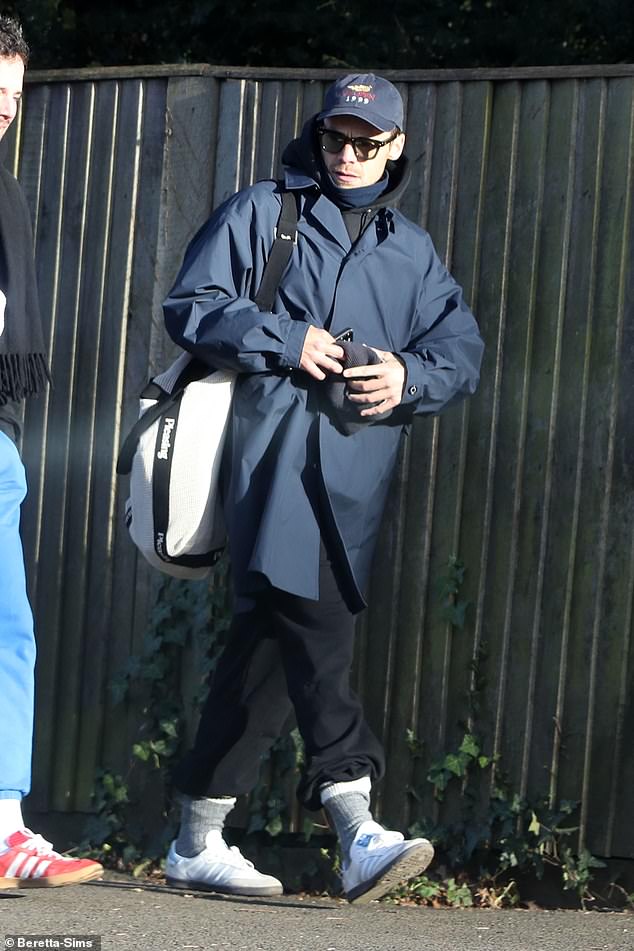 Harry dressed warmly after the cold swim in a black tracksuit and a navy blue raincoat