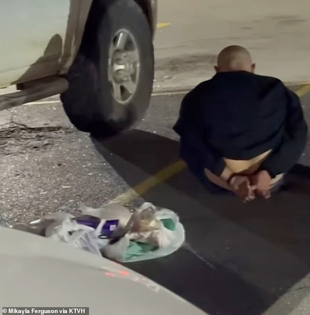 Caudle was handcuffed by police at the scene - he is pictured sitting next to Ferguson's car after the incident