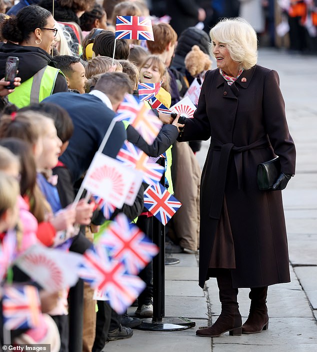 Camilla shakes hands with a crowd of flag-waving children as she fulfills her obligations while her husband, the King, recovers from surgery