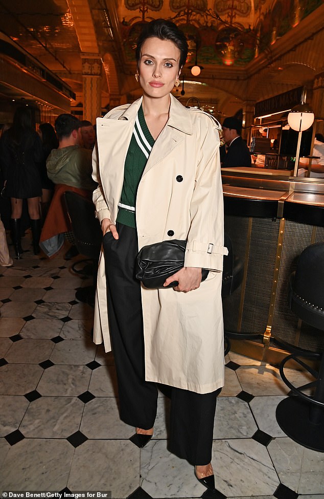 Wallis Day turned heads in a beige trench coat that she threw over a green sweater and black pants