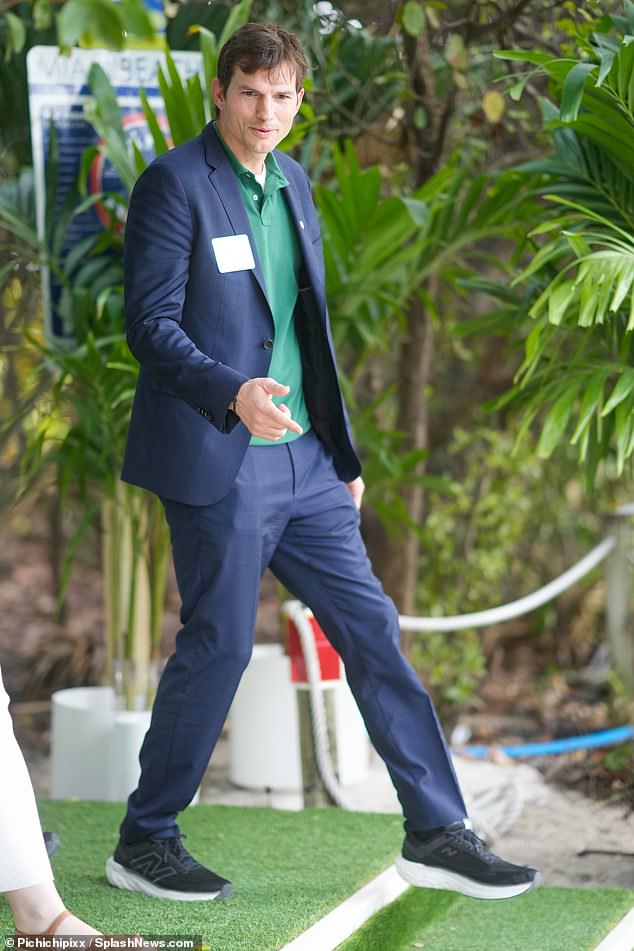 Ashton looked sharp in a navy blue suit, styled with a green polo shirt and black sneakers