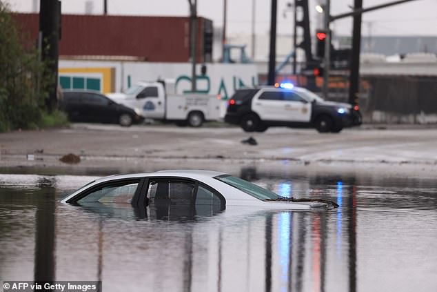 Numerous streets and highways in the state were flooded Thursday morning due to the pouring rain.  A car is seen submerged on a flooded road in Long Beach, California