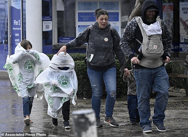 Tourists walk along the Embarcadero in San Diego to avoid the heavy rain