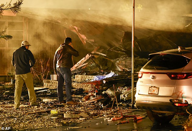 Investigators examine the burned remains of a mobile home after a plane crash Thursday