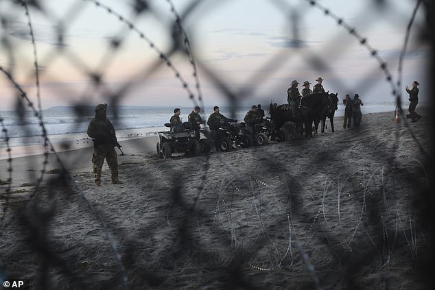 Armed US Border Patrol agents are seen on the US side of the border wall