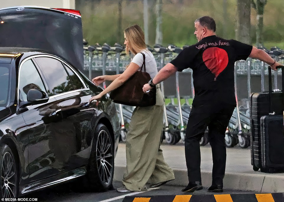 Margot helped herself open the car door before a man held it so she could step inside