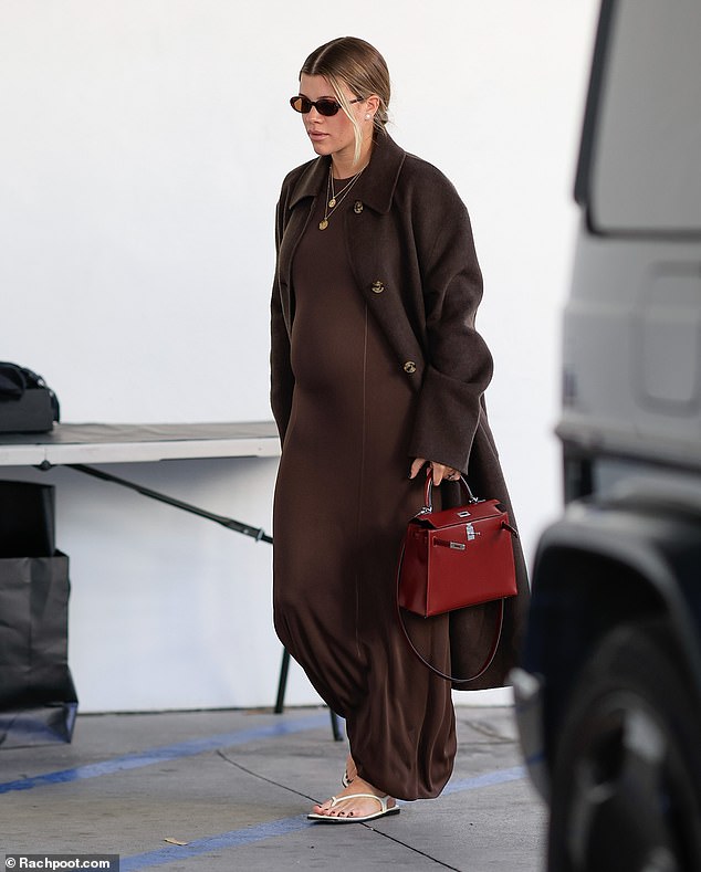 The 25-year-old model looked every bit the fashionista as she showed off her pregnancy bump in a chic brown dress and matching coat