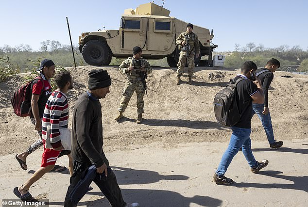 Immigrants from Venezuela pass Texas National Guard soldiers after crossing the Rio Grande into the United States on January 8 in Eagle Pass, Texas