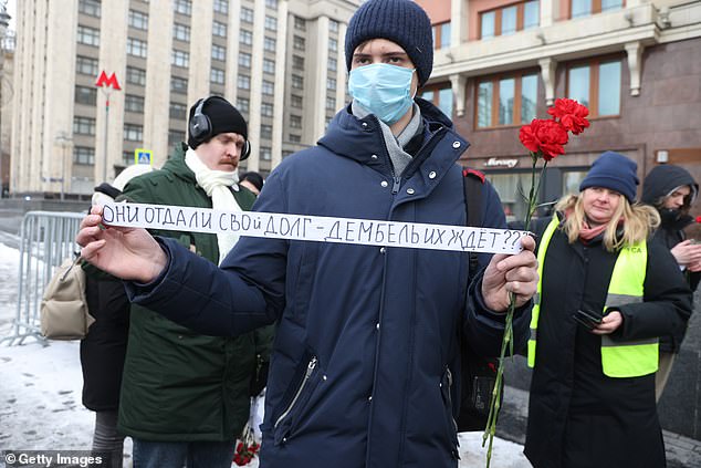 A man with a slogan on a ribbon that reads 'They paid their debt.  Is demobilization coming soon?'