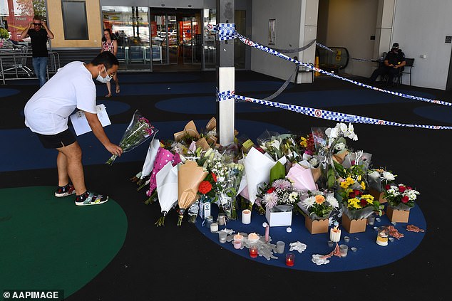 A local man is pictured leaving a floral tribute for Mrs White at the shopping center where she died